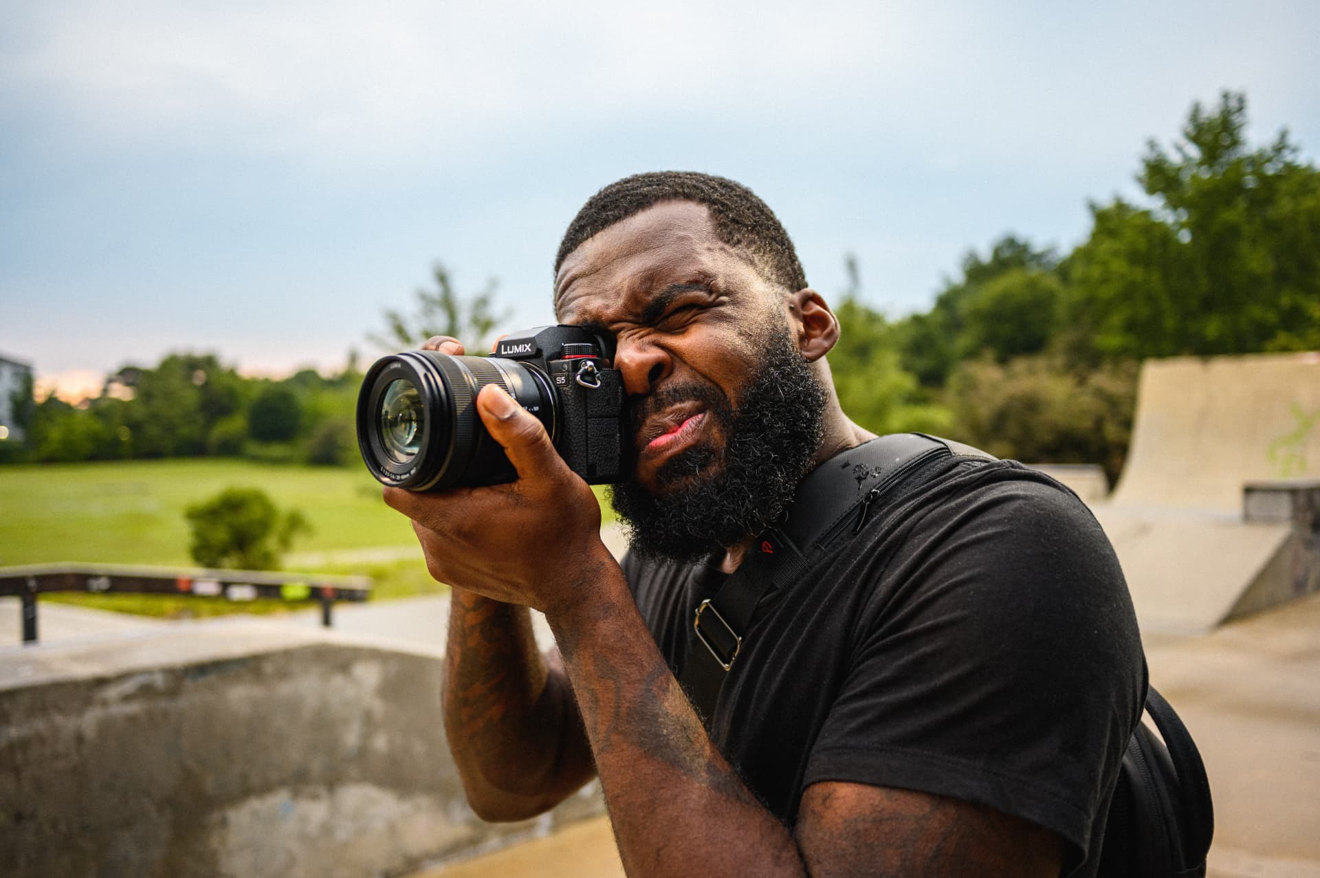 André Davis squinting through a LUMIX camera while shooting at an outdoor skatepark.