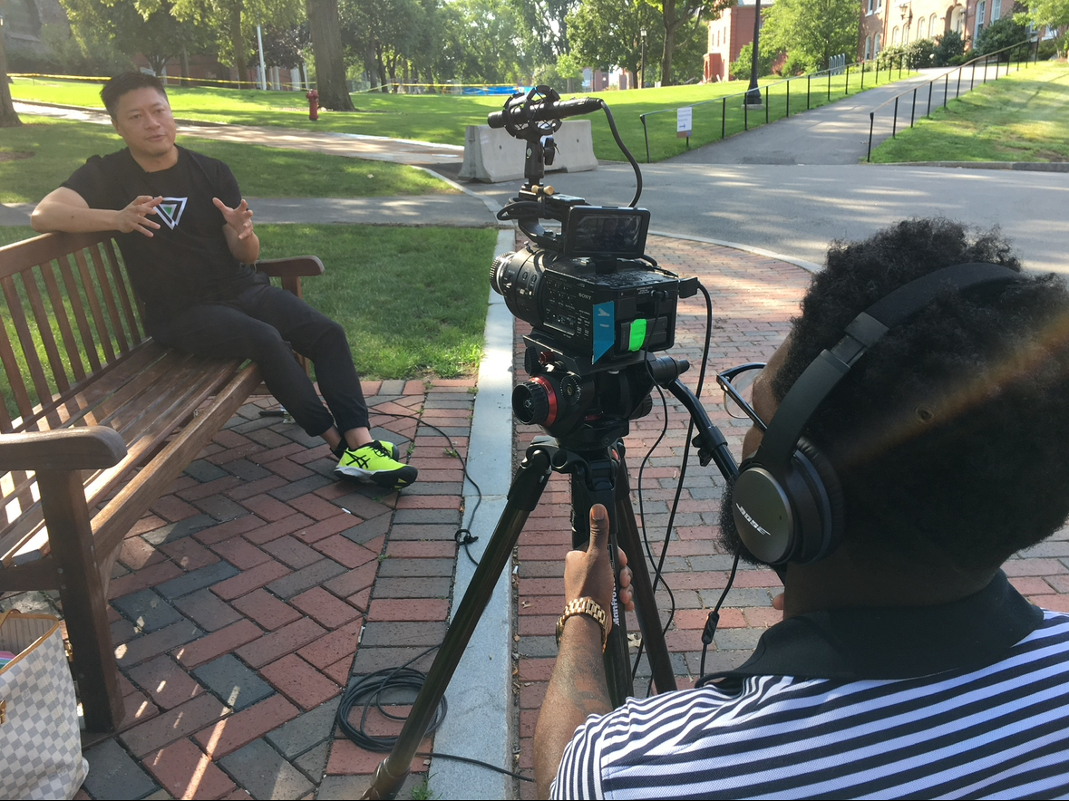 André Davis operating a camera during an outdoor interview shoot.