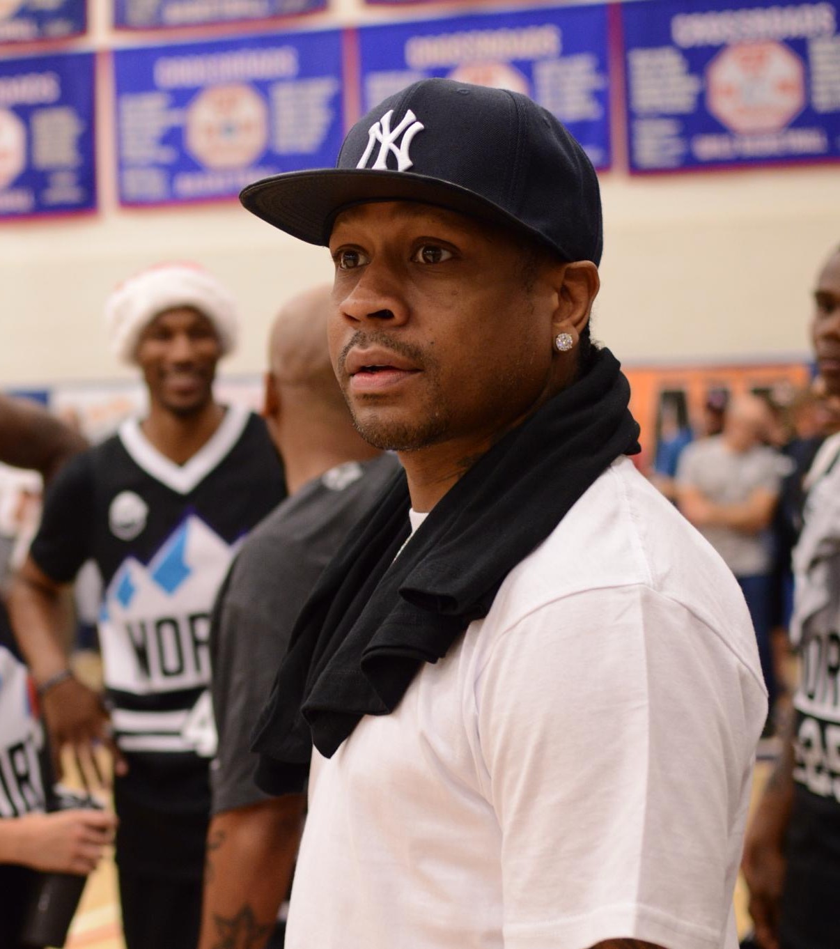 A man in a Yankees cap looks toward the court at a basketball event.
